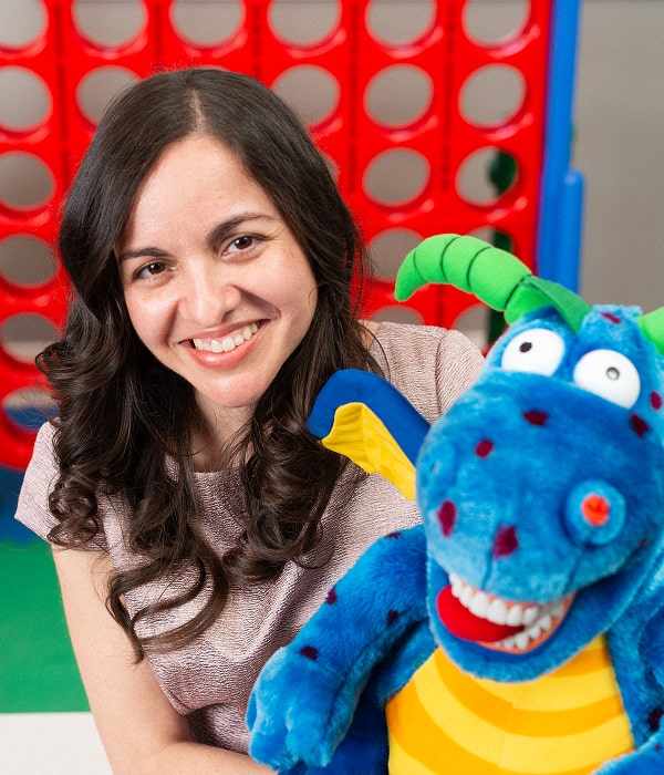 Dr. Brendaliz is smiling with a dragon toy in her hands