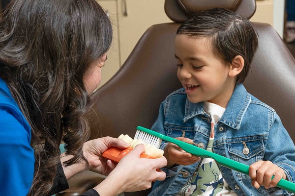 A boy in a dental chair having fun with his dentist