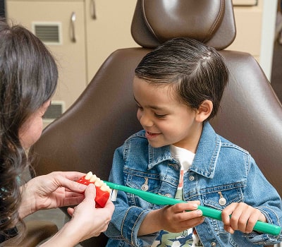 A boy in a jacket is smiling at Pediatric Dental clinic