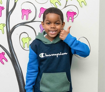 A boy is smiling and showing thumbs up