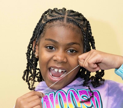 A girl is happily flossing her teeth