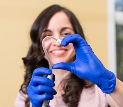 A woman in a nitrile gloves is making heart with a dental equipment
