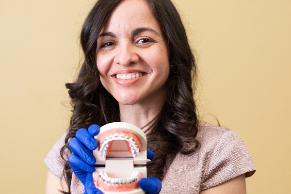 A dentist is smiling while holding dental model of a jaw