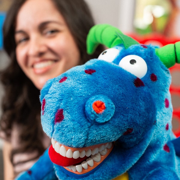 A woman is smiling with a children toy in her hands