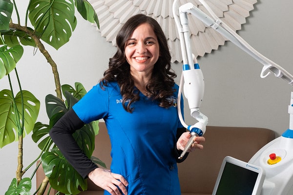 Dentist holding dental laser and smiling