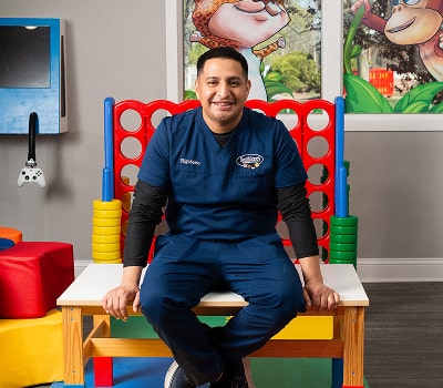 Dentist is sitting in a child's room and smiling at South Jersey pediatrics