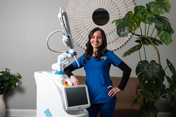 Dentist is smiling near dental laser machine