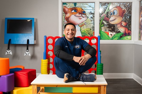 Dentist is smiling while sitting on the table