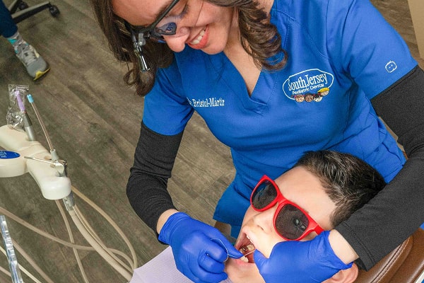 Dentist performing regular cleanings and smiling