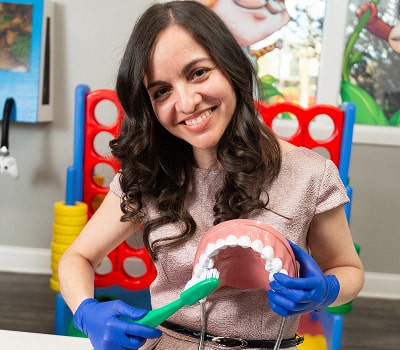 Dentist showcasing brushing techniques with a toothbrush and a model of a jaw