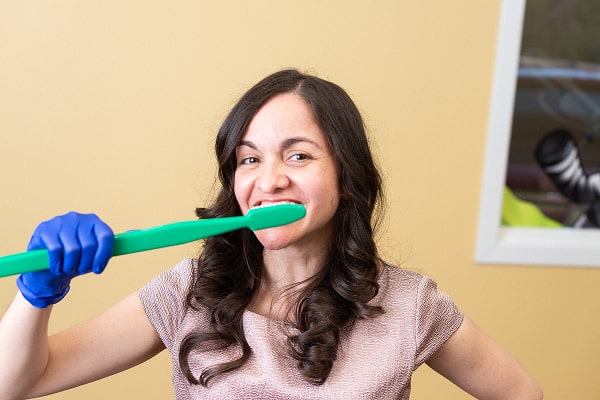 Dentist showcasing how to brush teeth with a huge tooth brush and a smile