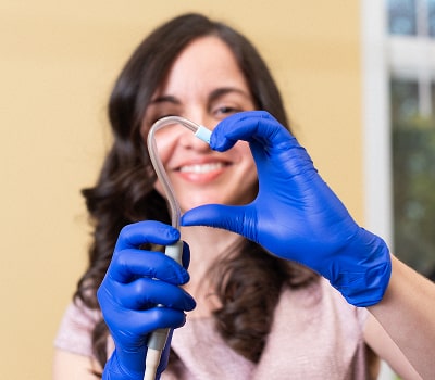 Dr. Brendaliz is happily and making heart with her hand and dental equipment