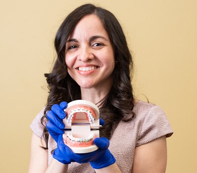 Dr. Brendaliz is happily smiling and showcasing a model of a jaw