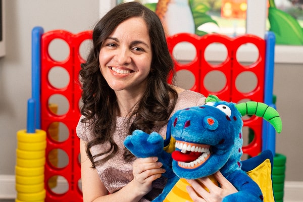 Dr. Brendaliz is smiling and holding dragon toy