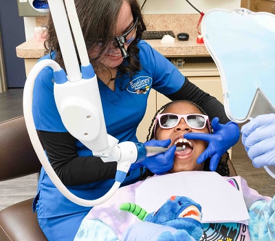 Dr. Brendaliz is smiling and performing dental laser procedure