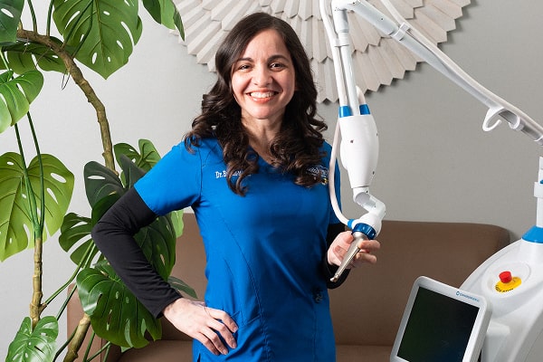 Dr. Brendaliz is smiling near dental laser