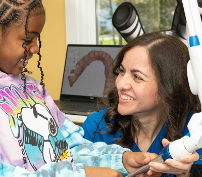 Dr. Brendaliz is smiling with a girl in a dental chair
