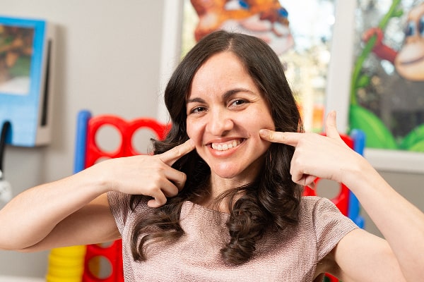 Dr. brendaliz is happily smiling and pointing to her healthy smilie