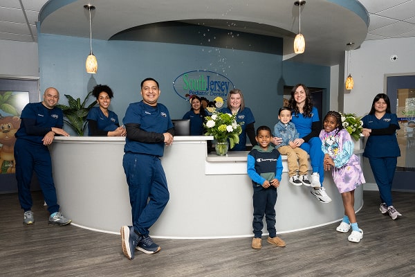 South Jersey Team is smiling with a happy patient at front desk