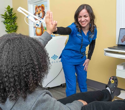 Top dentist having fun with young patient in a dental chair - both smiling