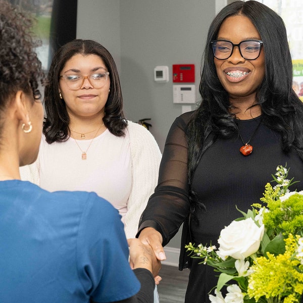 Two women are smiling one wearing braces